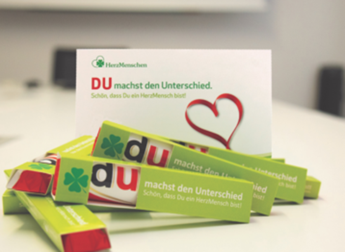 Grüne HerzMenschen Schokoladen und Karte mit "DU machst den Unterschied".