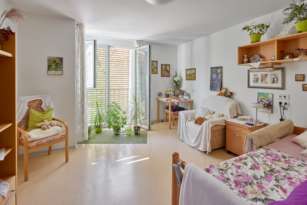 Helles Zimmer mit Pflanzen und Möbeln.