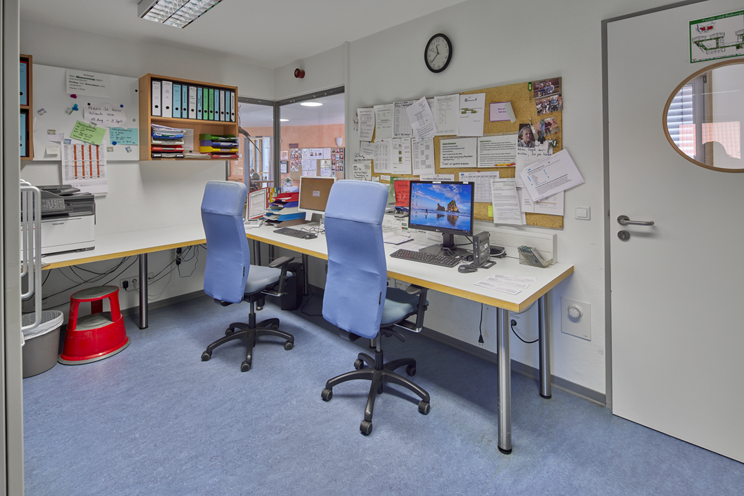 Büro mit Schreibtischen, Stühlen und Computern.