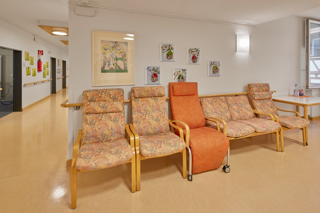 Wartebereich mit Stühlen und Kunst an der Wand.