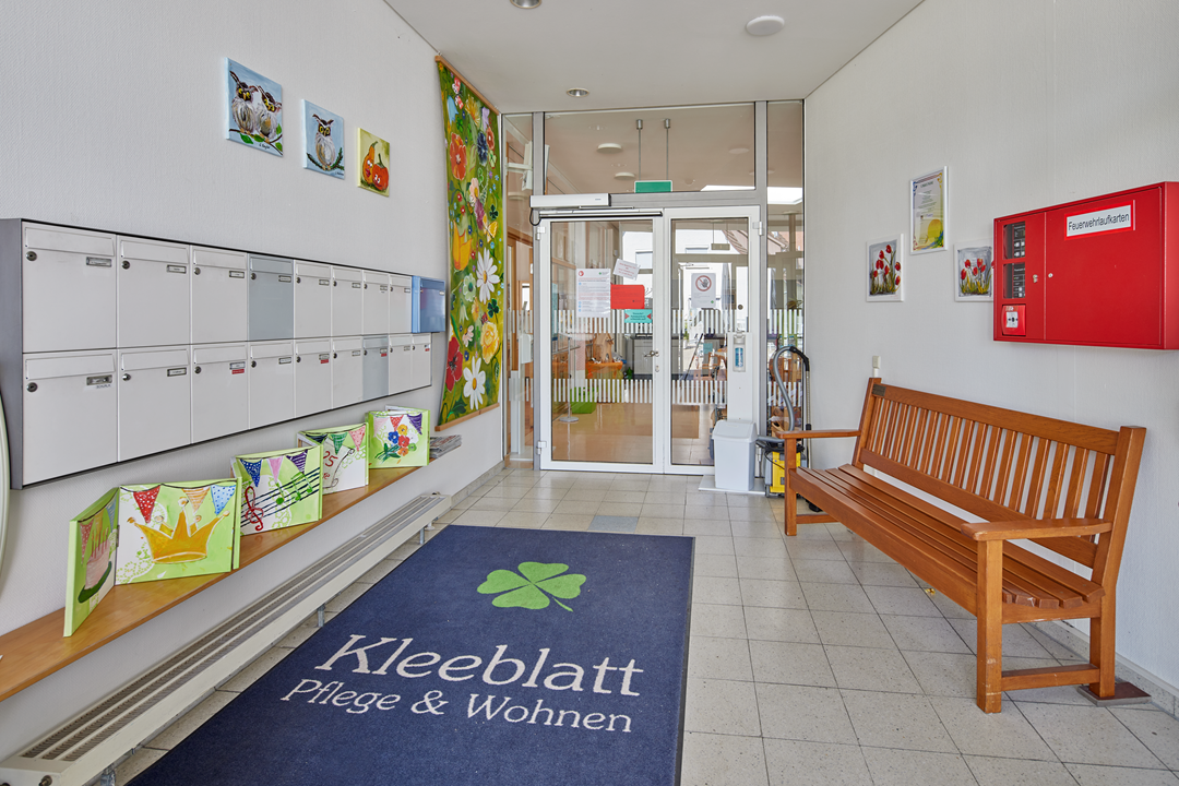 Eingangsbereich mit Sitzbank und Kunstwerken.