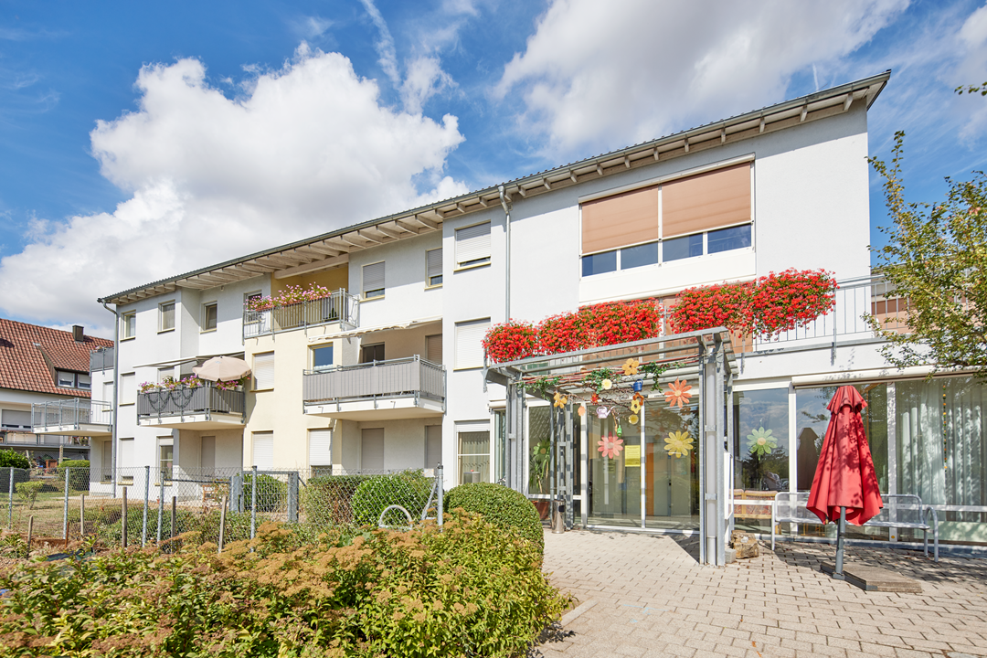 Mehrfamilienhaus mit Balkonen und Blumen.