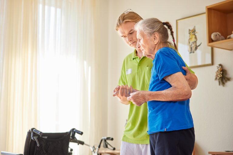 Pfleger hilft Seniorin beim Gehen