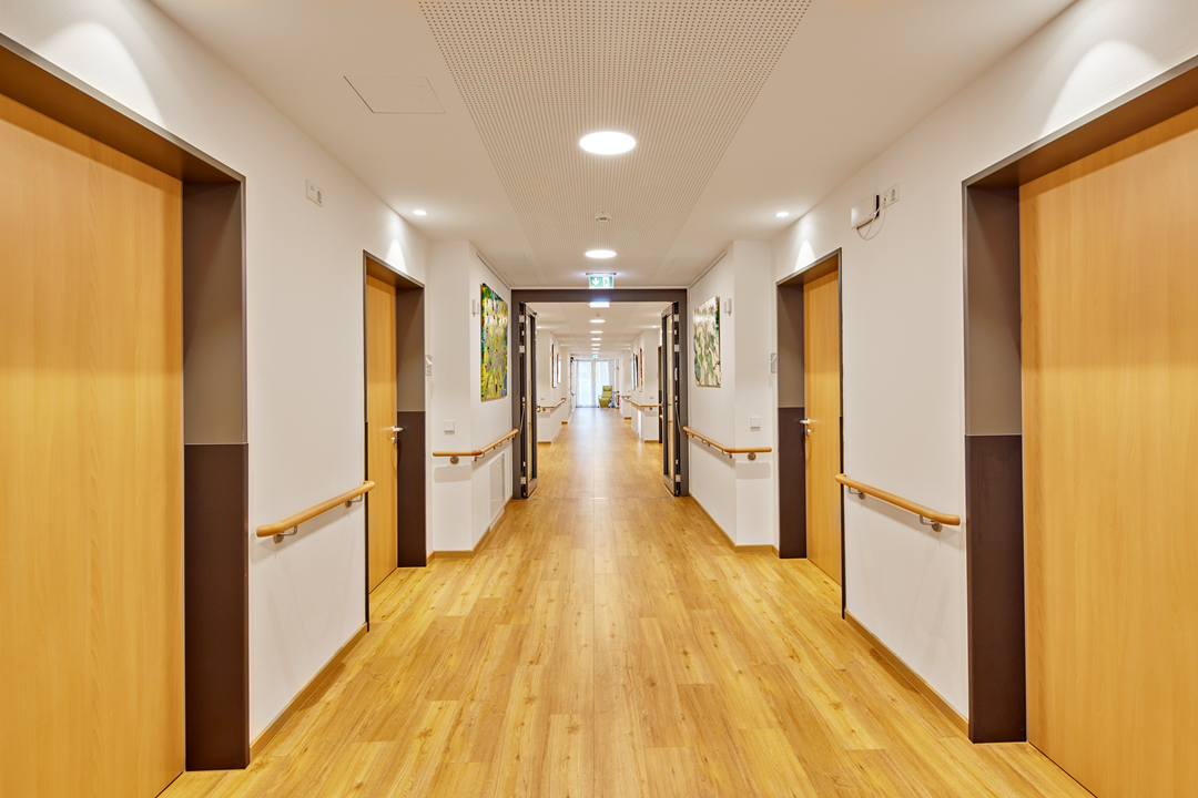 Moderner Krankenhausflur mit Holzboden und Beleuchtung.