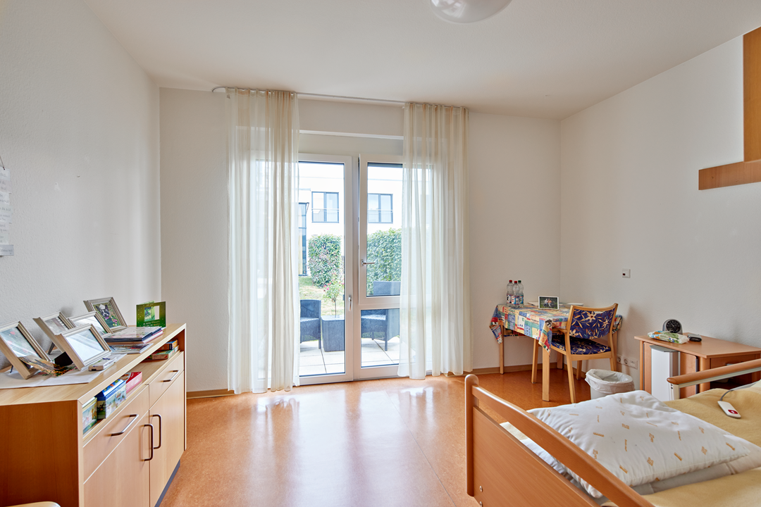 Helles Zimmer mit Bett und Balkonblick.