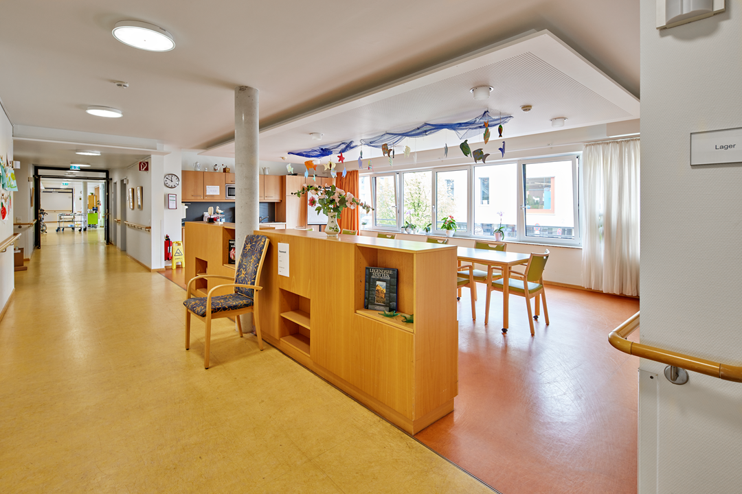 Helle Lounge im Pflegeheim mit Tisch, Stühlen.