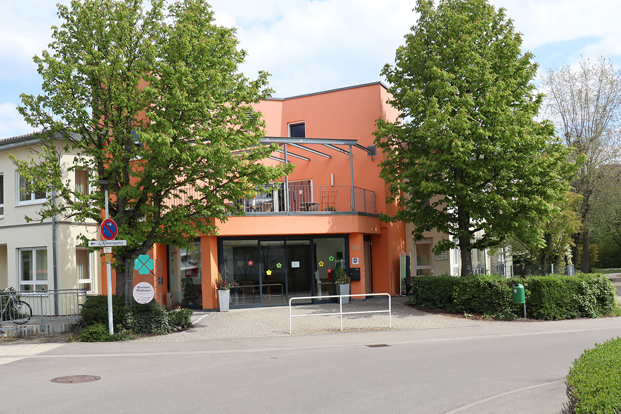 Modernes Gebäude mit orangener Fassade und Bäumen.