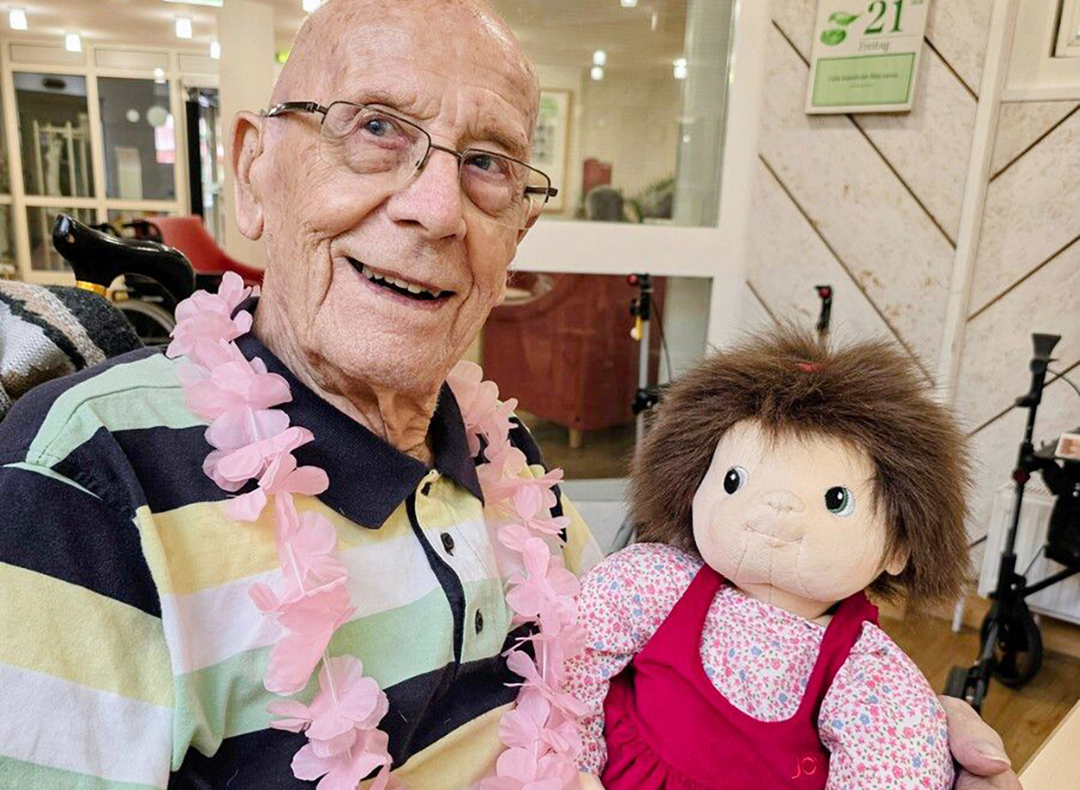 Lächelnder älterer Mann mit Lei und Puppe.