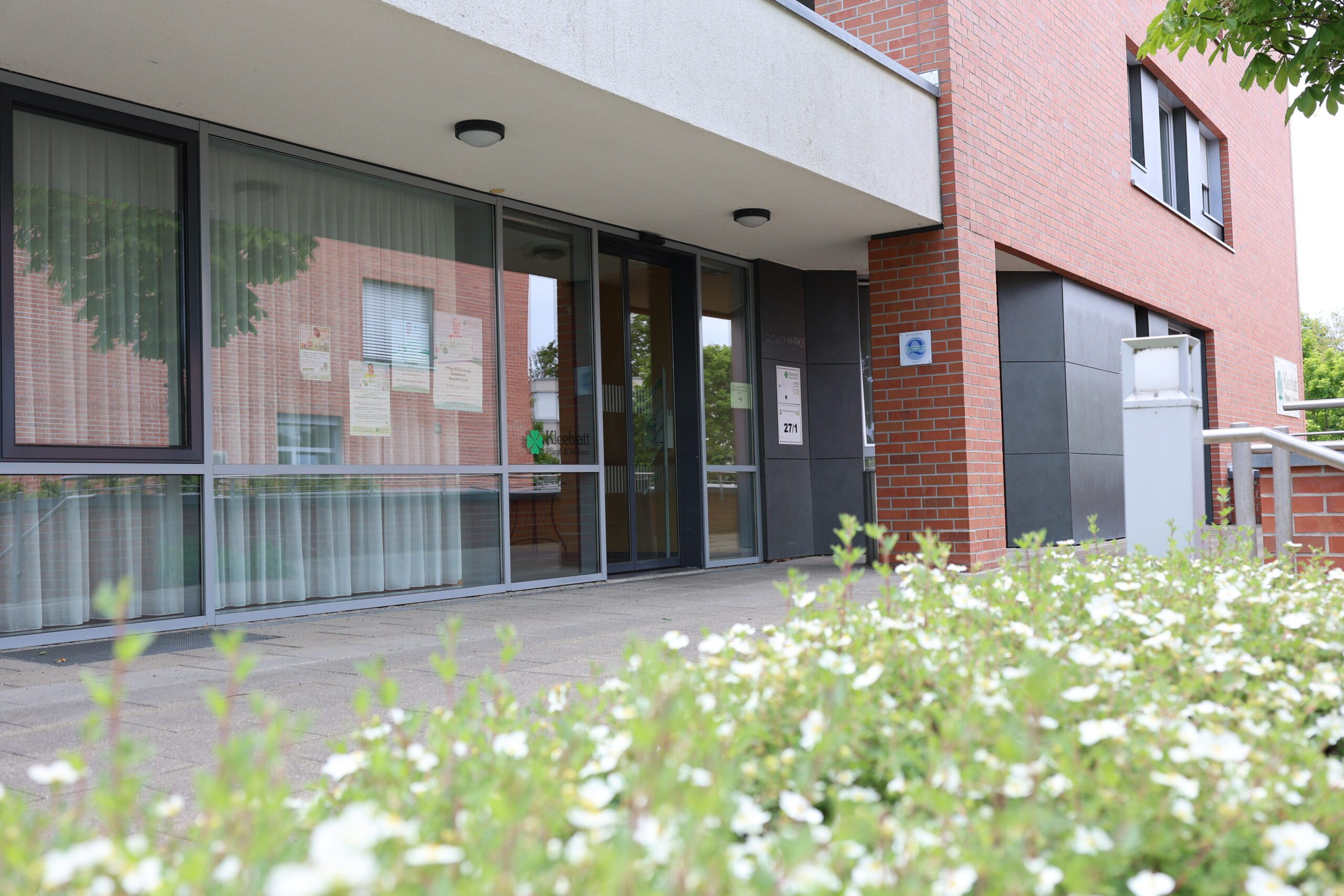 Eingang eines modernen Gebäudes mit Schildern.