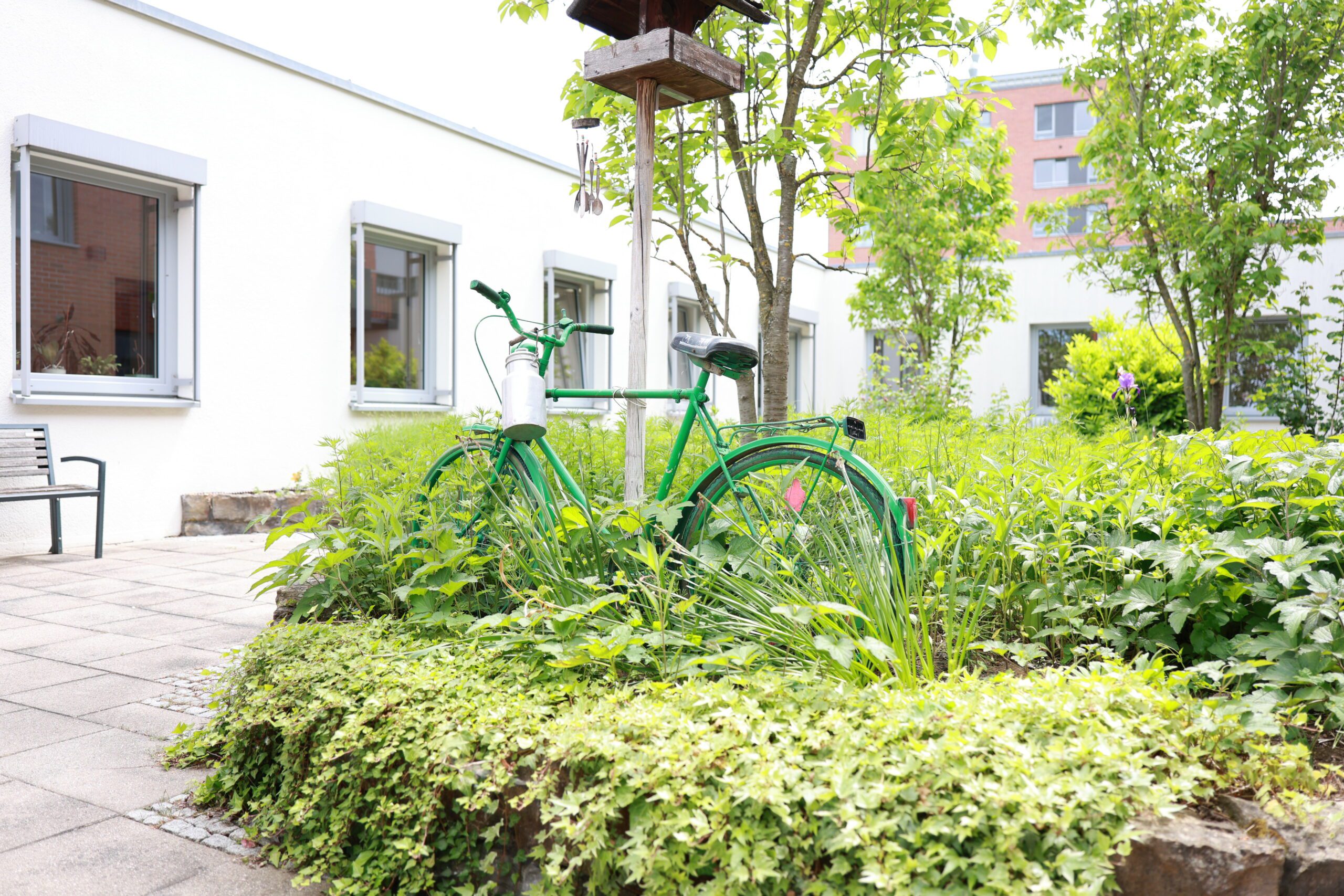 Grünes Fahrrad im Garten neben Gebäude.