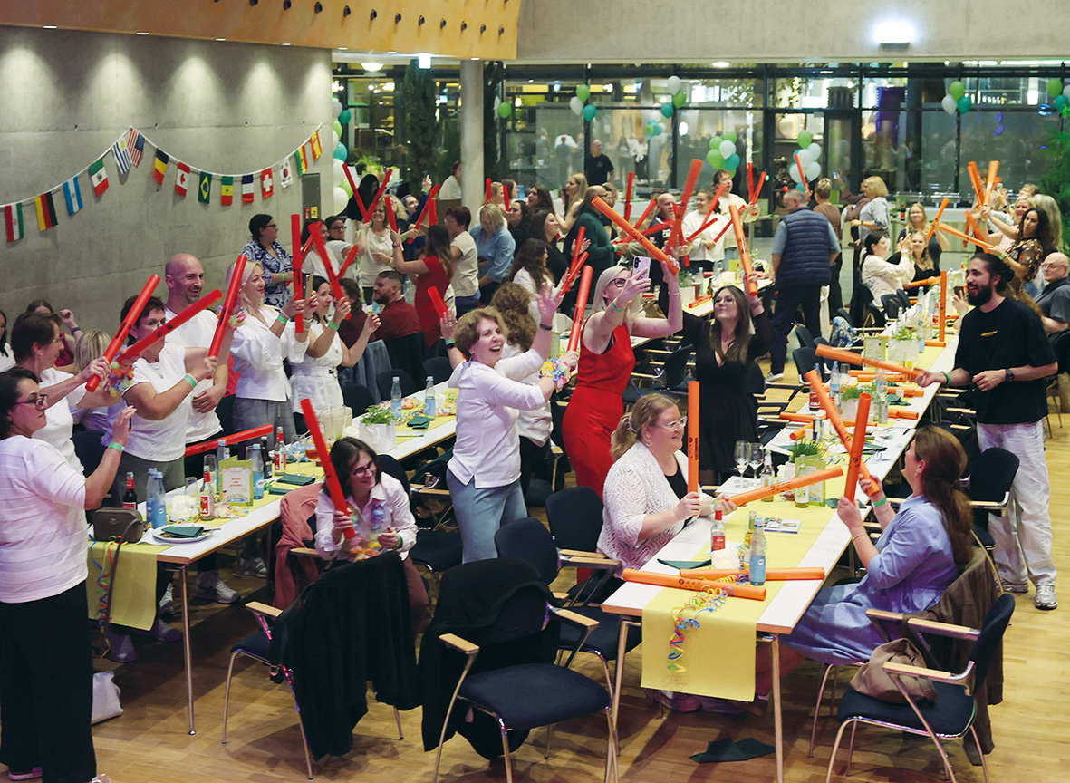 Fröhliche Gruppe feiert mit Schaumstoffstäben bei internationalem Event.
