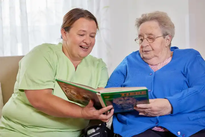 Pflegerin liest älterer Frau ein Buch vor.