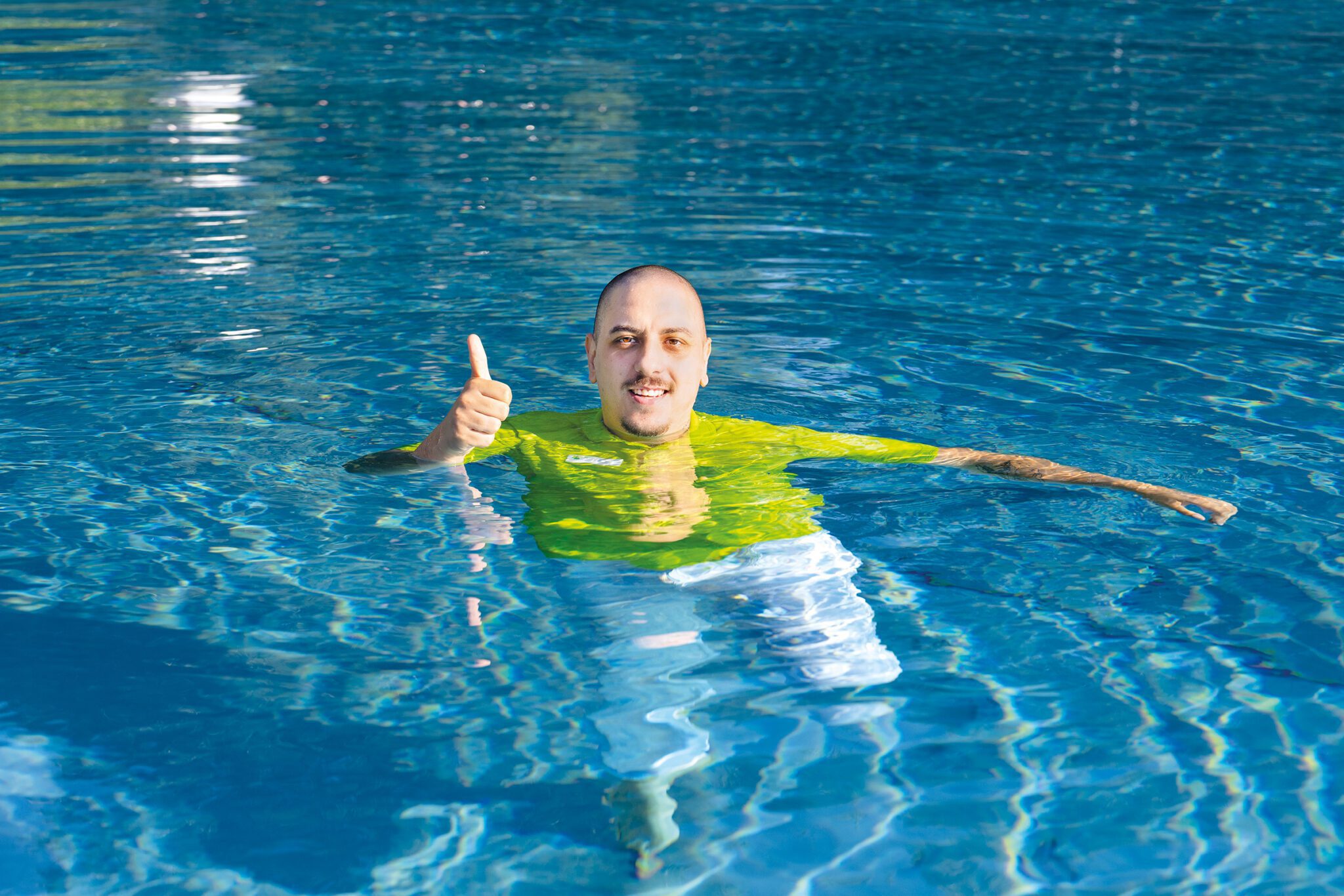 Mann im Pool mit Daumen hoch