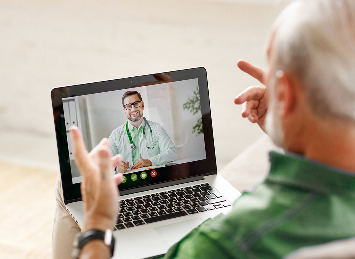 Älterer Mann spricht mit Arzt per Videocall auf Laptop.
